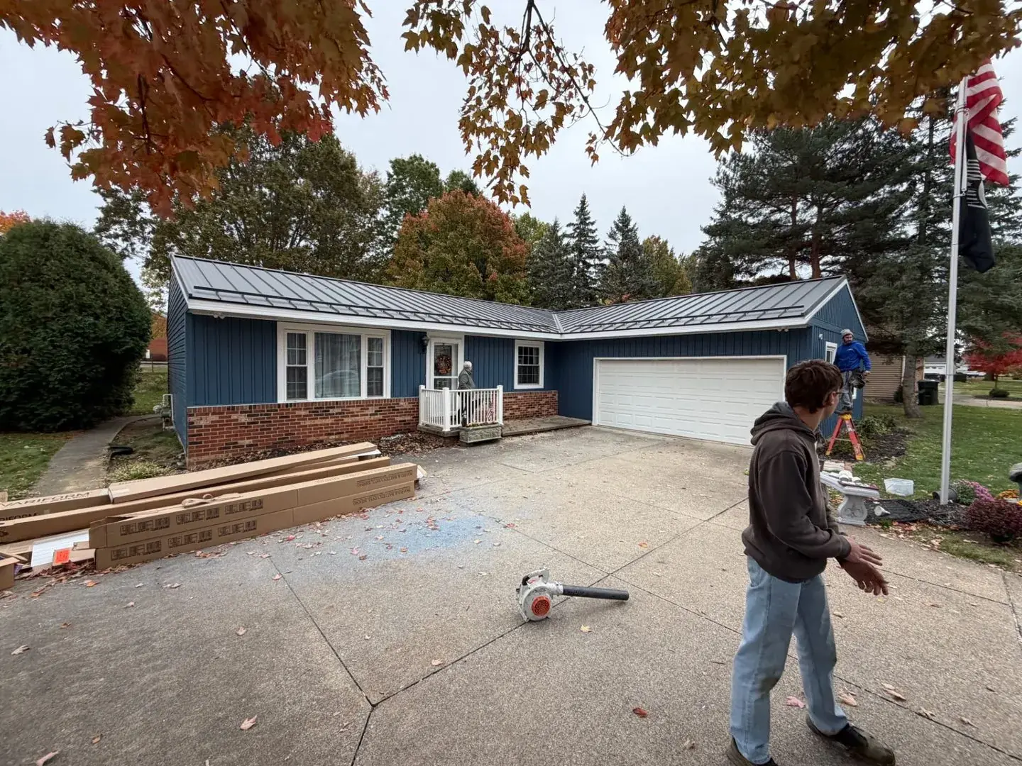 Blue vinyl siding with metal roof installation