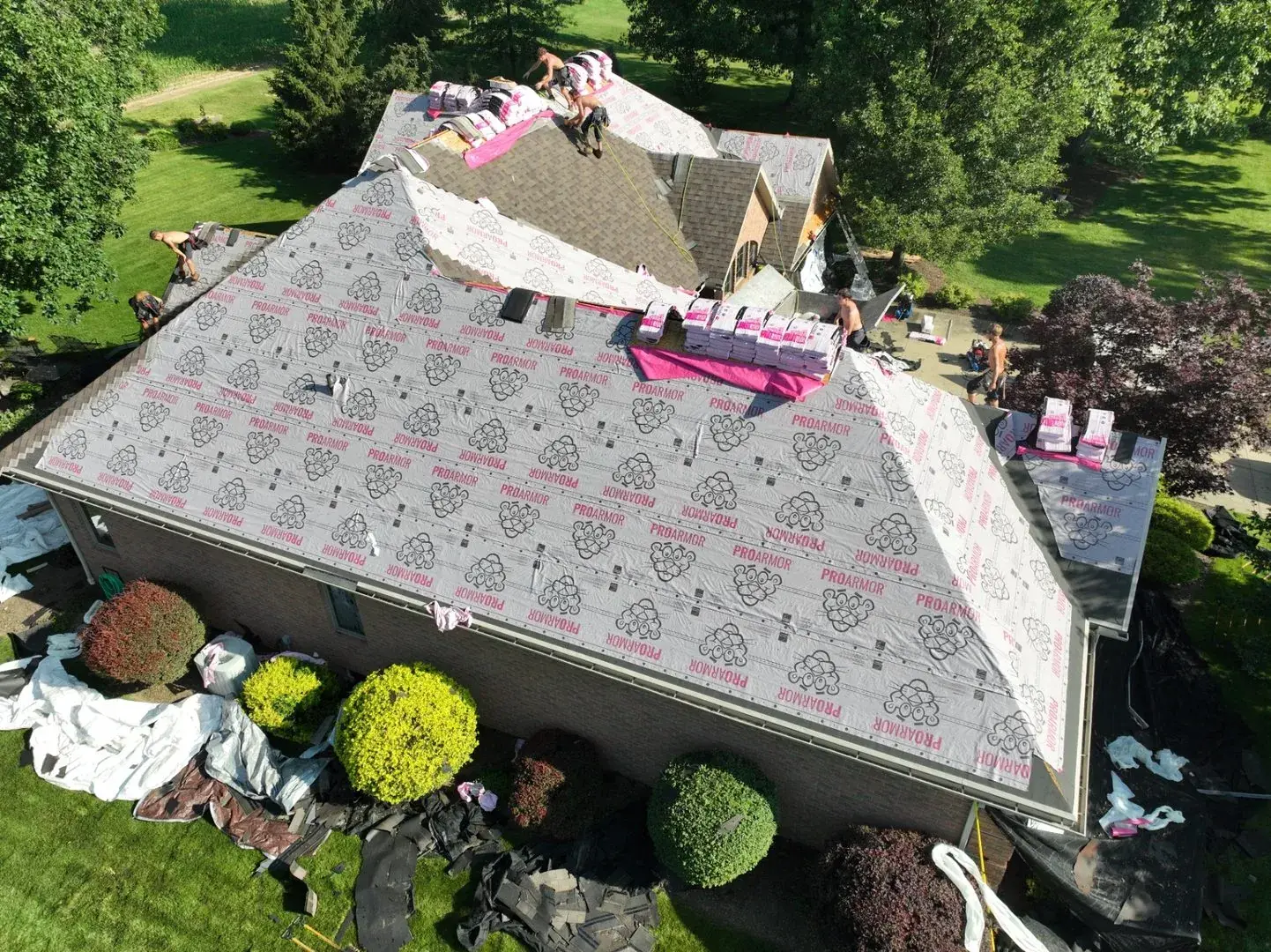 Cornerstone crew installing underlayment across a hip roof, photographed from the air