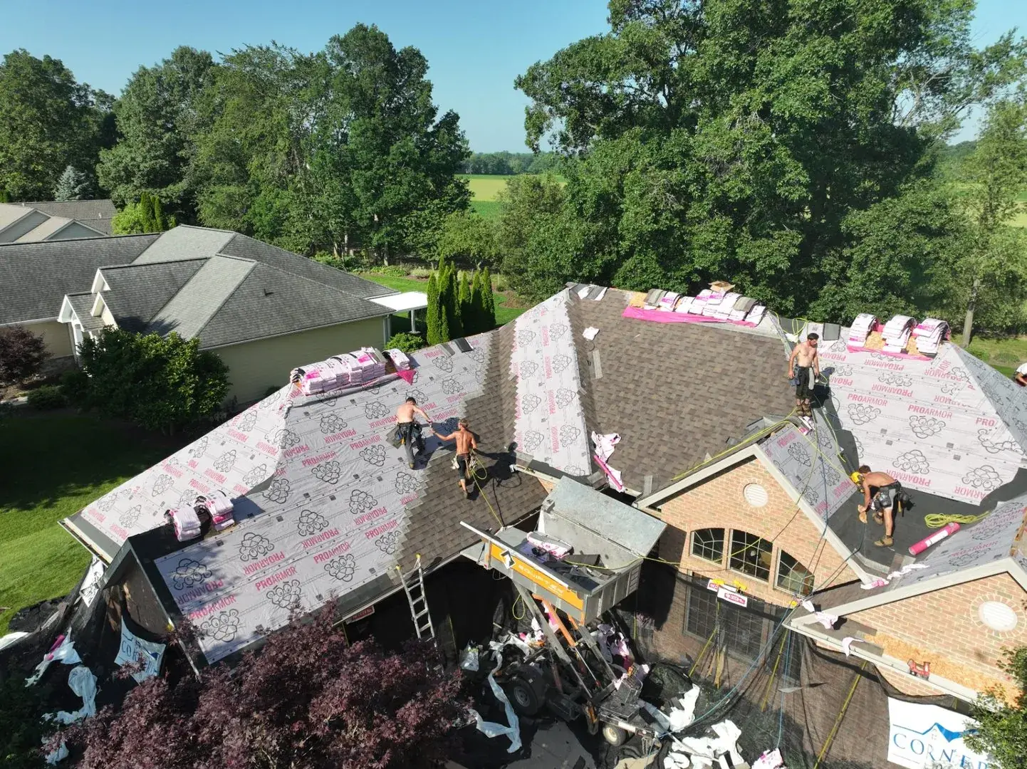 Cornerstone crew working on the roof of a two-story home with the driveway staged below
